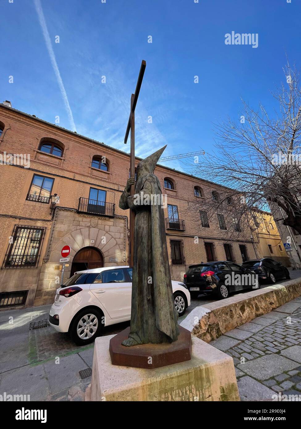 Segovia, Spagna - 18 febbraio 2022: Statua dell'uomo che tiene una grande croce, indossa un tradizionale abito cerimoniale con cappello a punta e maschera. Foto Stock