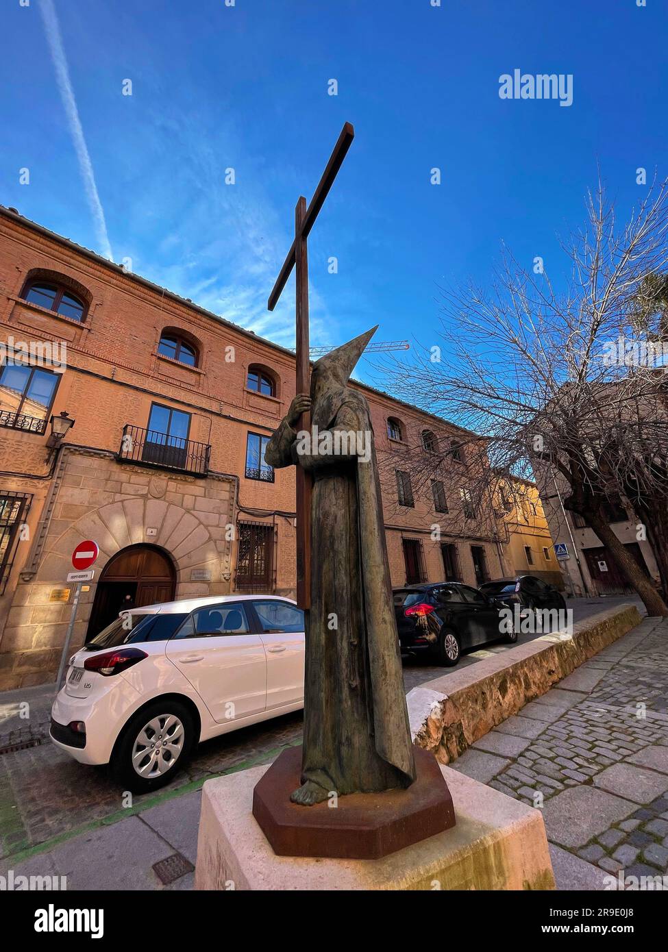 Segovia, Spagna - 18 febbraio 2022: Statua dell'uomo che tiene una grande croce, indossa un tradizionale abito cerimoniale con cappello a punta e maschera. Foto Stock