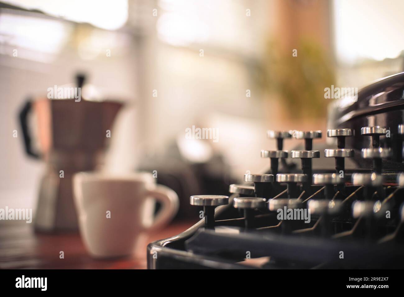 Vecchio. macchina da scrivere ben utilizzata con caffettiera e tazza espresso e messa a fuoco limitata Foto Stock
