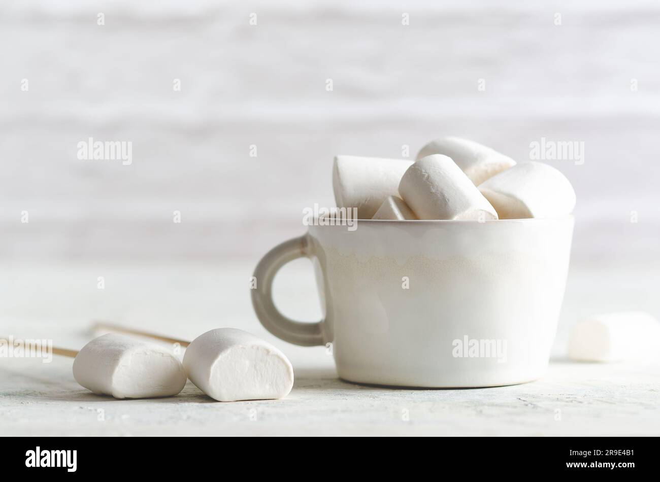 Marshmallow bianchi in una tazza bianca su sfondo bianco con spazio per la copia. Foto Stock