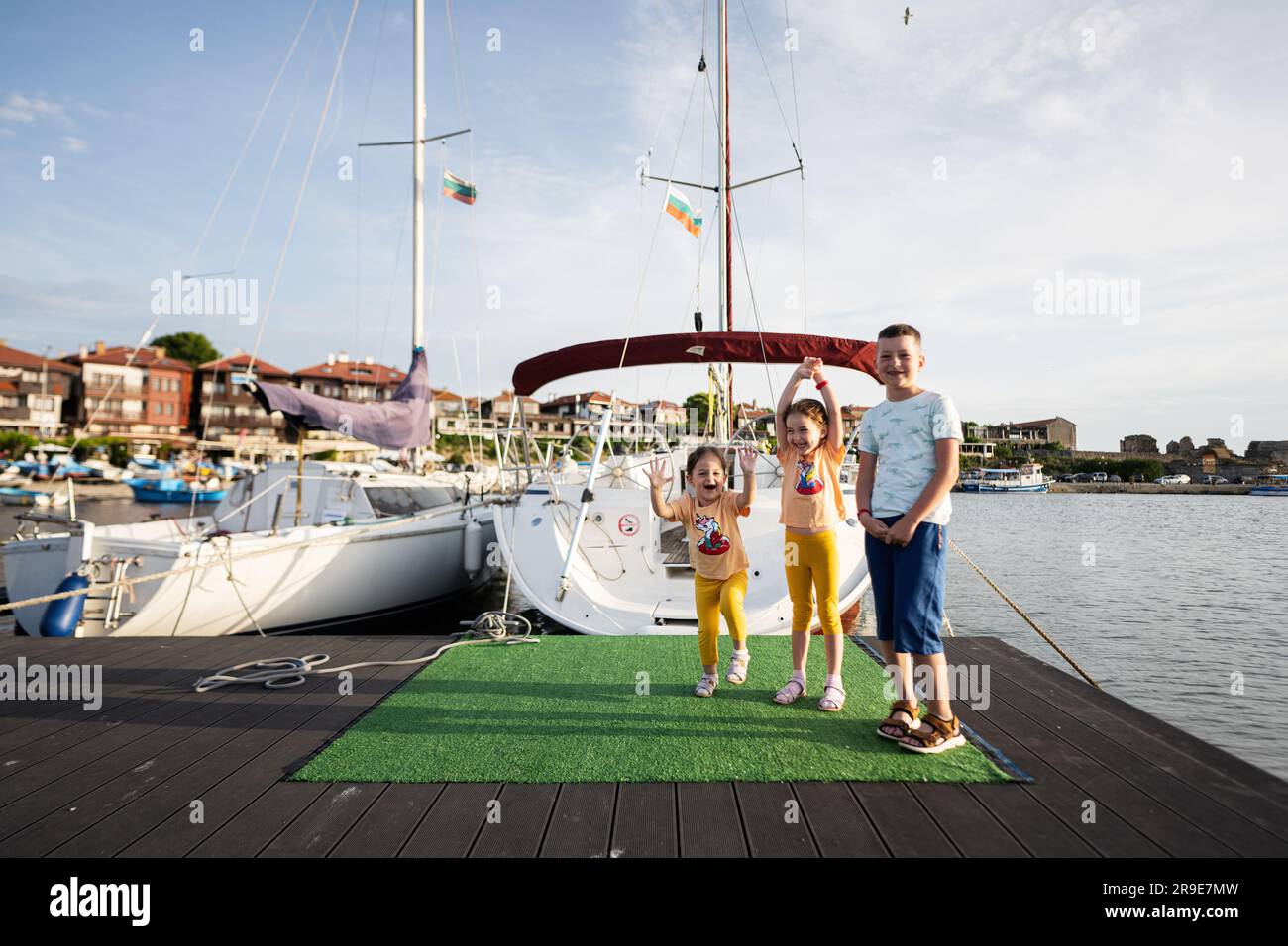 Bambini felici di tre persone in piedi su un molo con barche sullo sfondo Nessebar, Bulgaria. Foto Stock