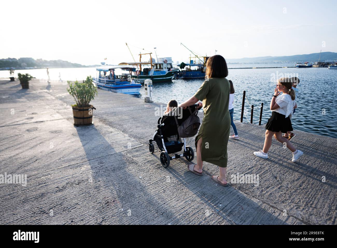 Madre e figlia camminano con il passeggino sul molo la sera. Foto Stock