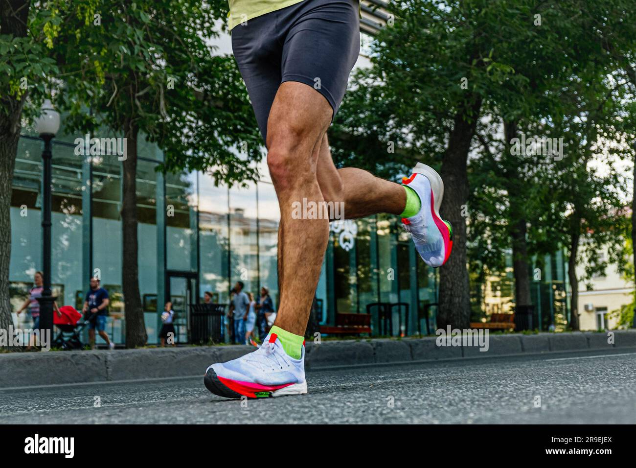 gambe da vicino atleta di corsa maschile, tights neri e scarpe da running bianche brillanti Foto Stock