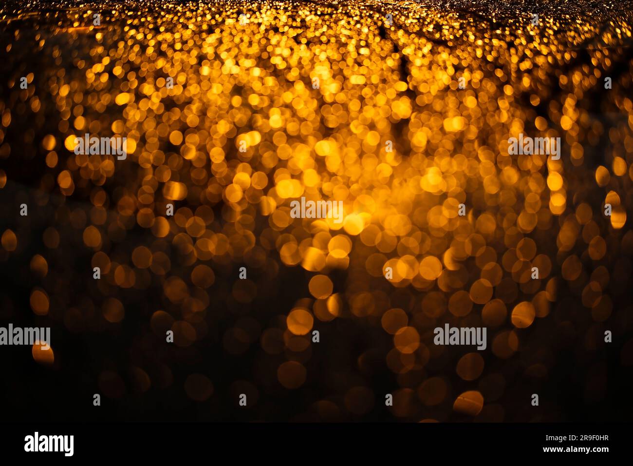 Luci bokeh arancioni sul cofano dell'auto di notte come sfondo astratto Foto Stock