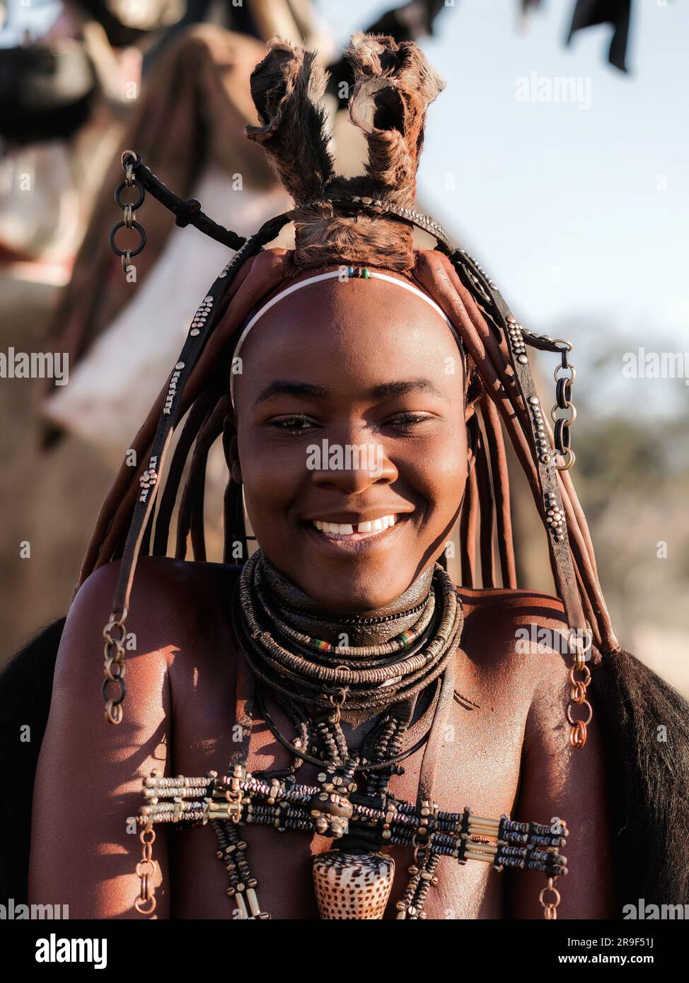 Giovane donna Himba sorridente, vestita in stile tradizionale nel suo villaggio in Namibia, in Africa. Foto Stock