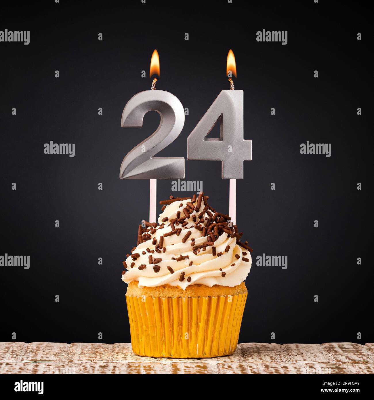 Cupcake di compleanno con candela numero 24 - celebrazione su sfondo scuro Foto Stock