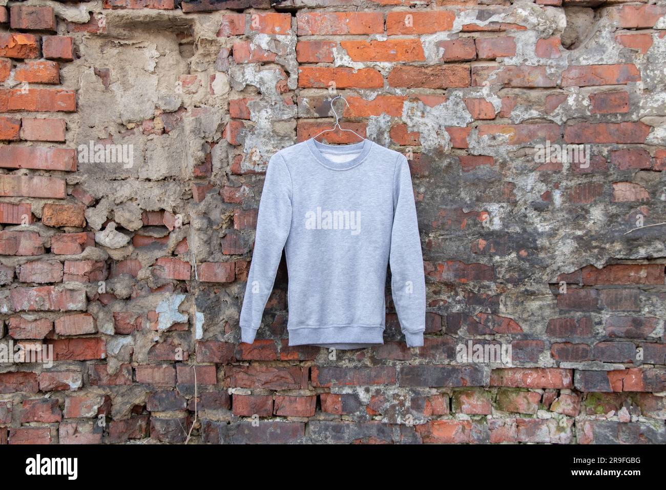 maglione leggero appeso a un appendiabiti su una parete di mattoni sulla strada, abbigliamento femminile di moda Foto Stock