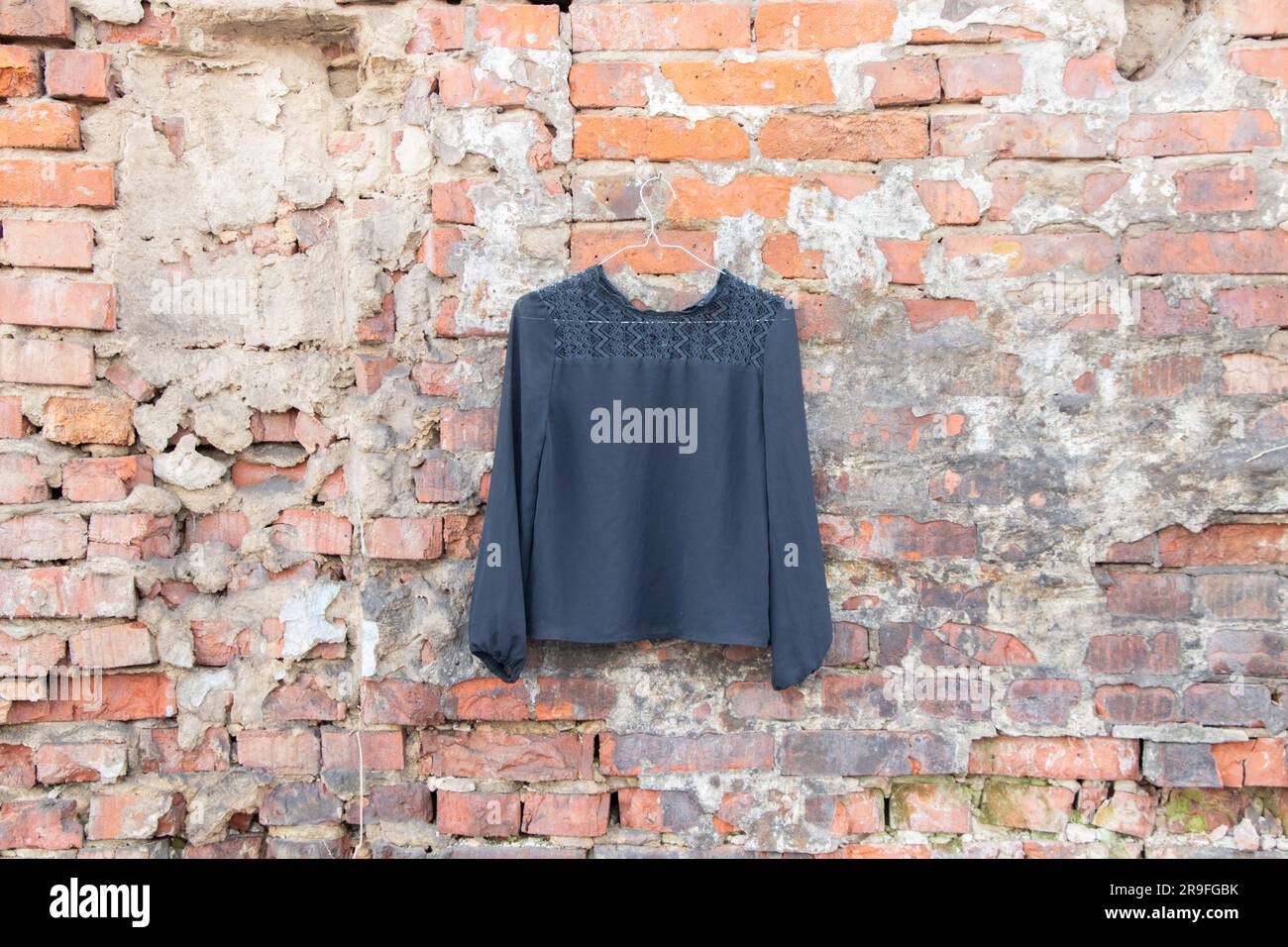 giacca nera appesa a un appendiabiti su un muro di mattoni in strada, abbigliamento femminile alla moda Foto Stock