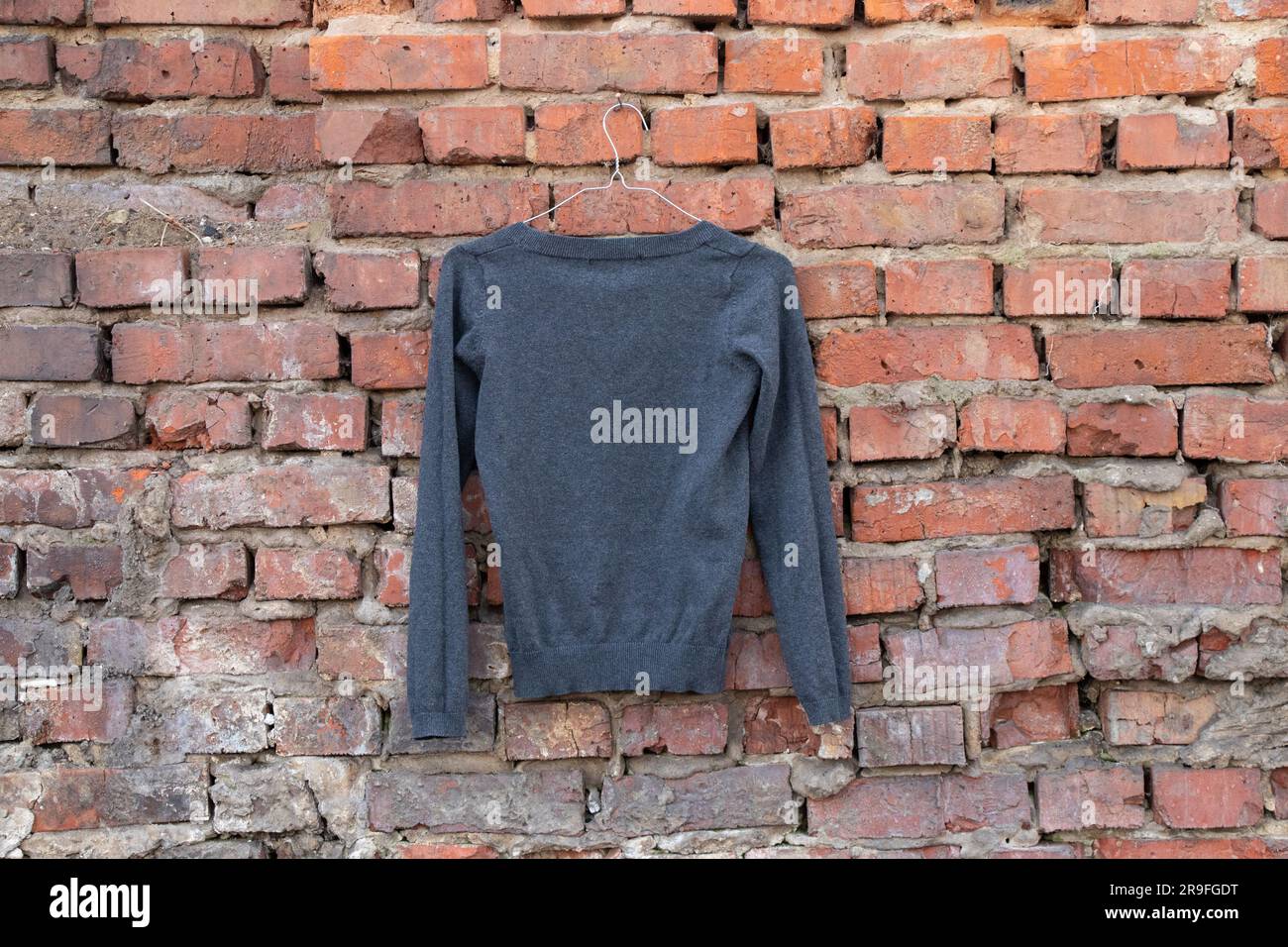 giacca nera appesa a un appendiabiti su un muro di mattoni in strada, abbigliamento femminile alla moda Foto Stock