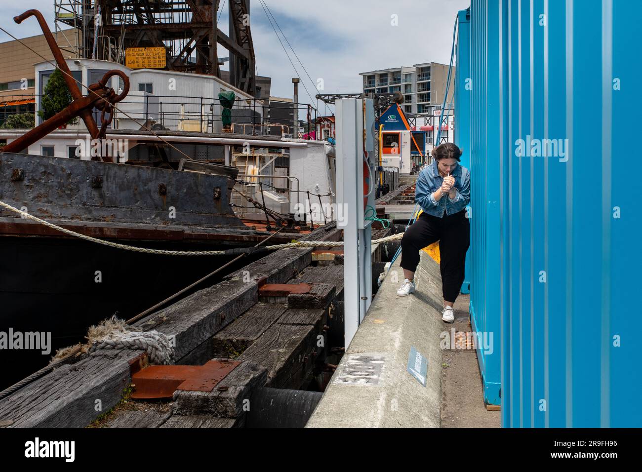 Una giovane ragazza prende una sigaretta subdola e si accende dietro un container nell'area del porto di Wellington, nuova Zelanda capitale. Foto: Rob Watkins Foto Stock