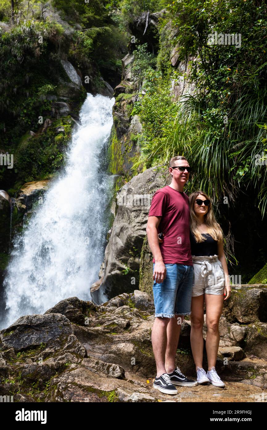 Una coppia posa alle cascate Wainui Falls Wainui Bay, Tasman Region, nuova Zelanda, South Island, Abel Tasman National Park. Foto: Rob Watkins Foto Stock