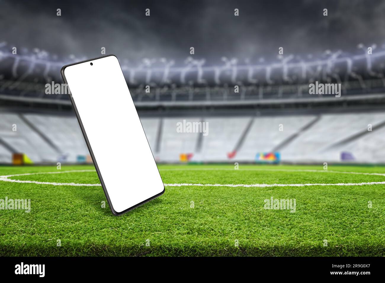 Modello di telefono nello stadio di calcio. Schermo isolato per la promozione delle app. Prato e si trova sullo sfondo Foto Stock