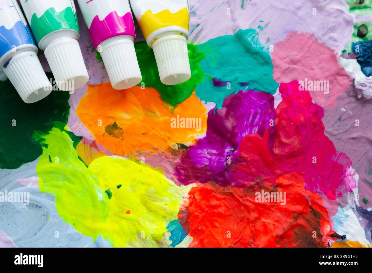 Sfondo, brillante astrazione multicolore di vari colori e quattro tubi di vernici nell'angolo superiore. Foto Stock