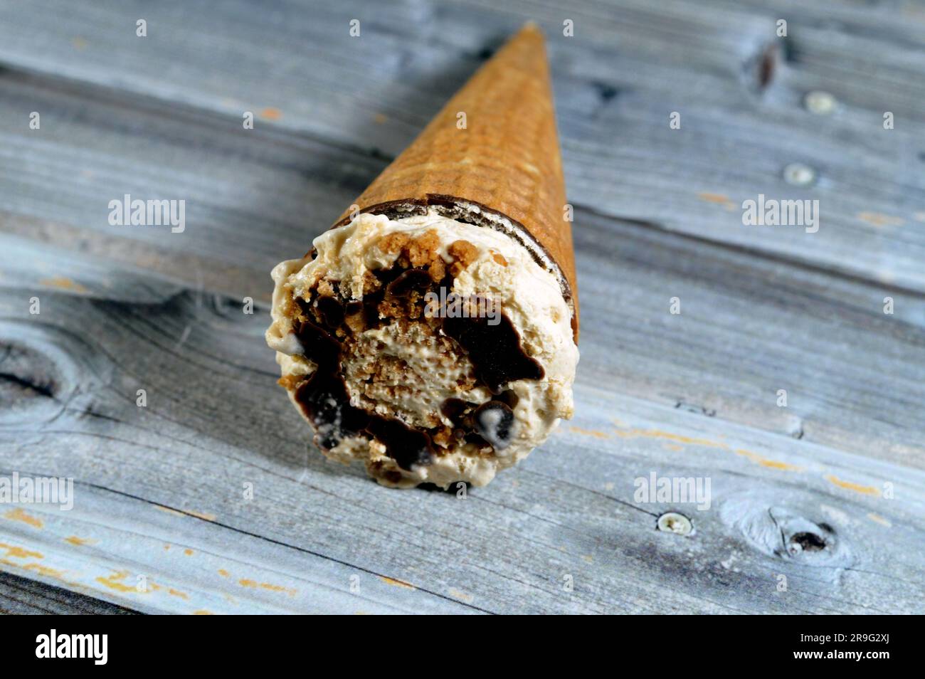 Biscotti caramellati gelato al cioccolato al cacao e cono alla vaniglia con condimento di biscotti e noci in coni di wafer croccanti, sciogliendo il ghiaccio freddo crea Foto Stock