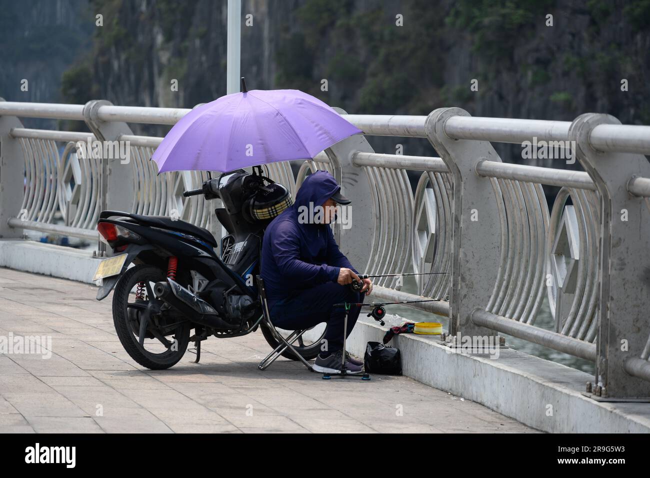 Ha Long, Vietnam -- 19 marzo 2023. Un uomo sta pescando da un ponte ad ha Long in Vietnam. Foto Stock