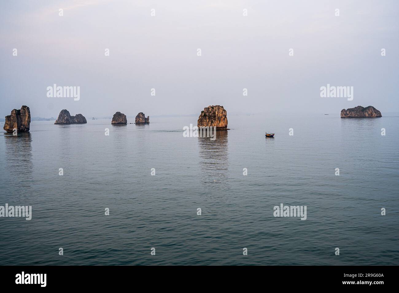 Foto delle formazioni rocciose nelle acque blu della baia di ha Long nel tardo pomeriggio. Foto Stock