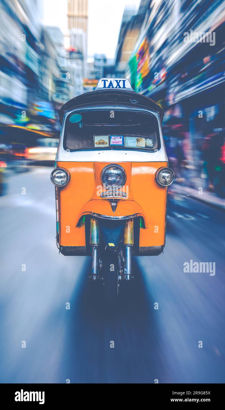 Un taxi Tuk-Tuk corre lungo Una strada trafficata di Bangkok Foto Stock