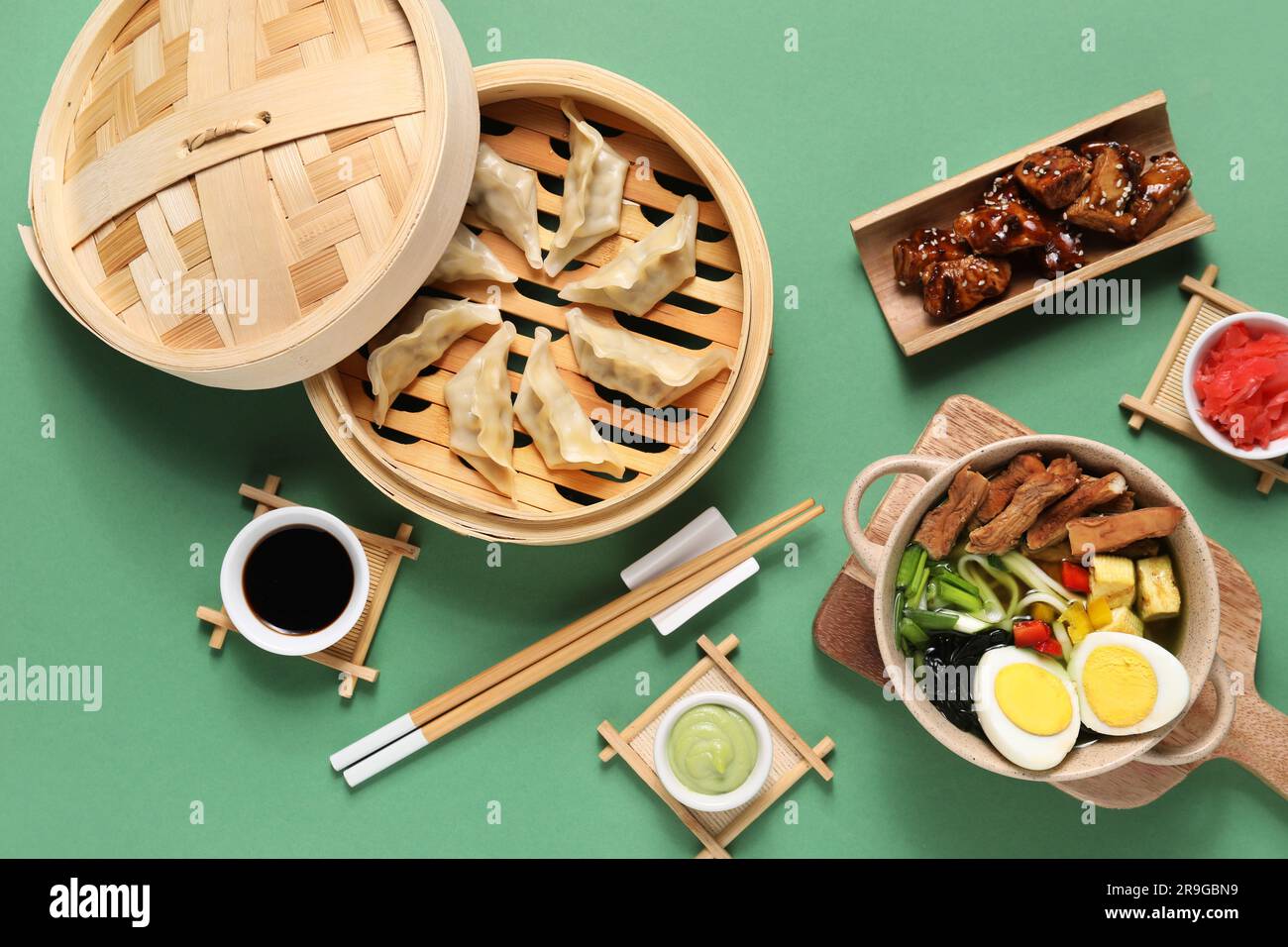 Composizione con gustosi piatti cinesi e bacchette su sfondo verde Foto Stock