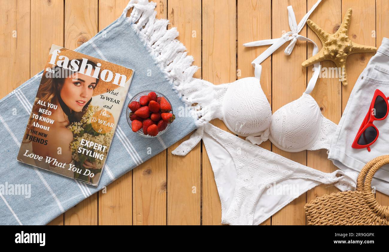 Ciotola di fragola con vestiti, accessori da spiaggia e telefono cellulare su un pontone di legno su sfondo verde. Concetto di viaggio Foto Stock