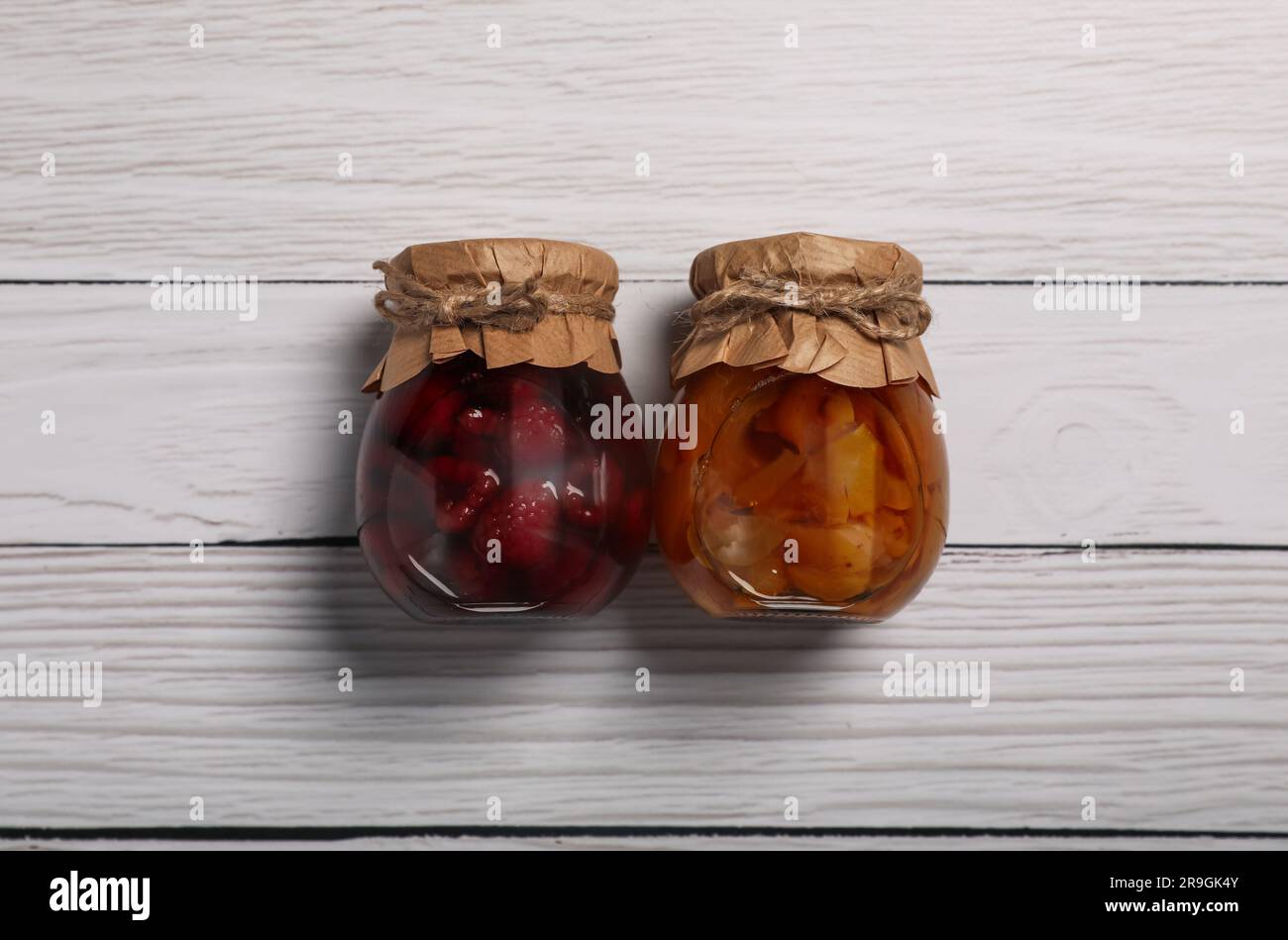 Barattoli con frutta sottaceto su un tavolo di legno bianco, piatti Foto Stock