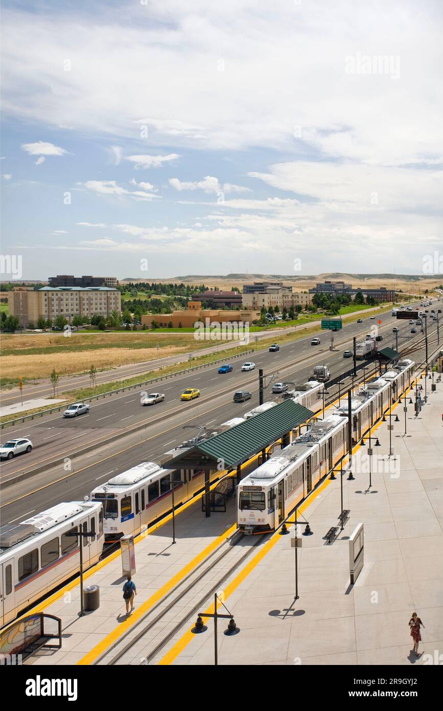 Treni della metropolitana leggera Segui l'interstate Highway arriva alla stazione vicino a Denver, Colorado Foto Stock