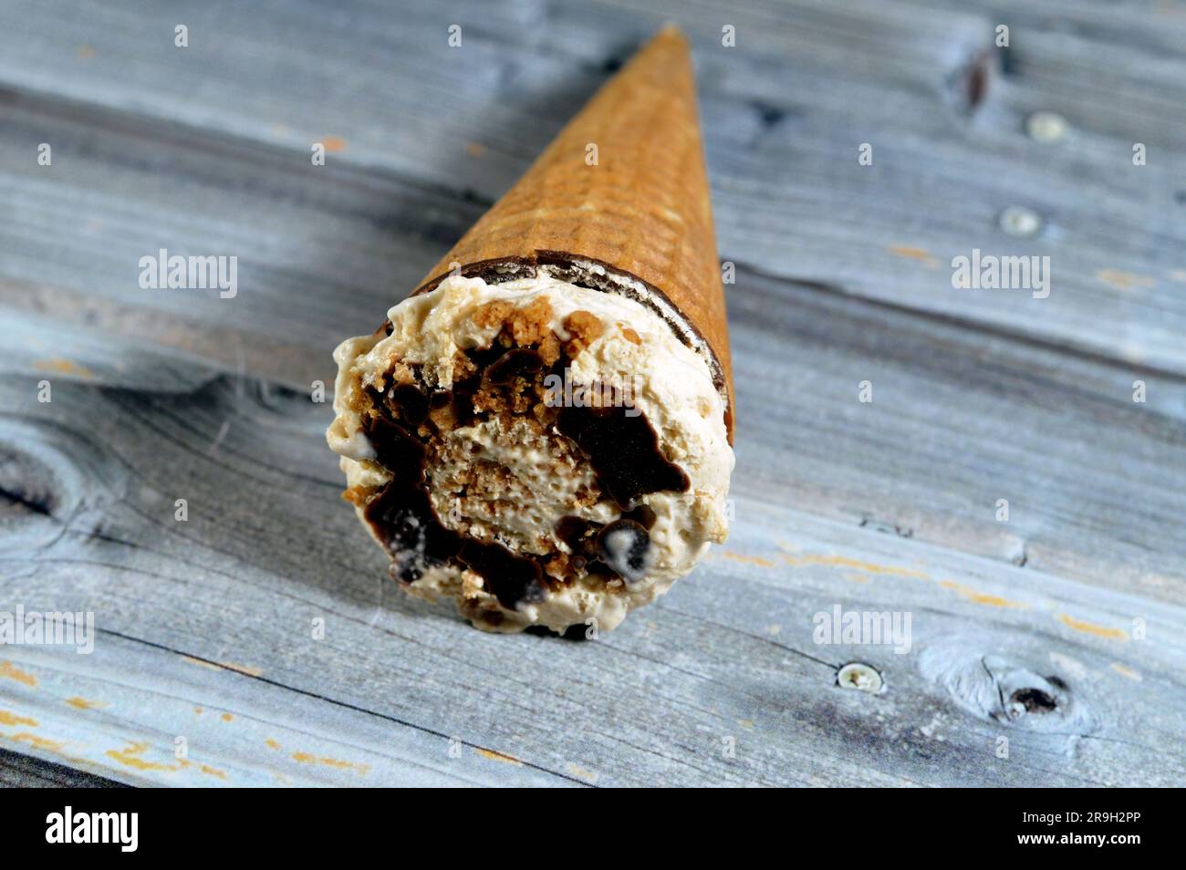 Biscotti caramellati gelato al cioccolato al cacao e cono alla vaniglia con condimento di biscotti e noci in coni di wafer croccanti, sciogliendo il ghiaccio freddo crea Foto Stock