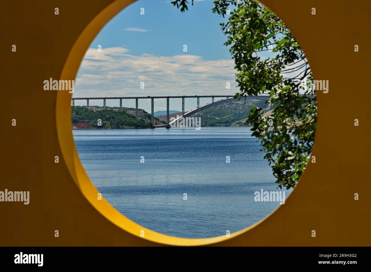 Ponte ad arco tra la terraferma e l'isola attraverso il buco in un muro Foto Stock