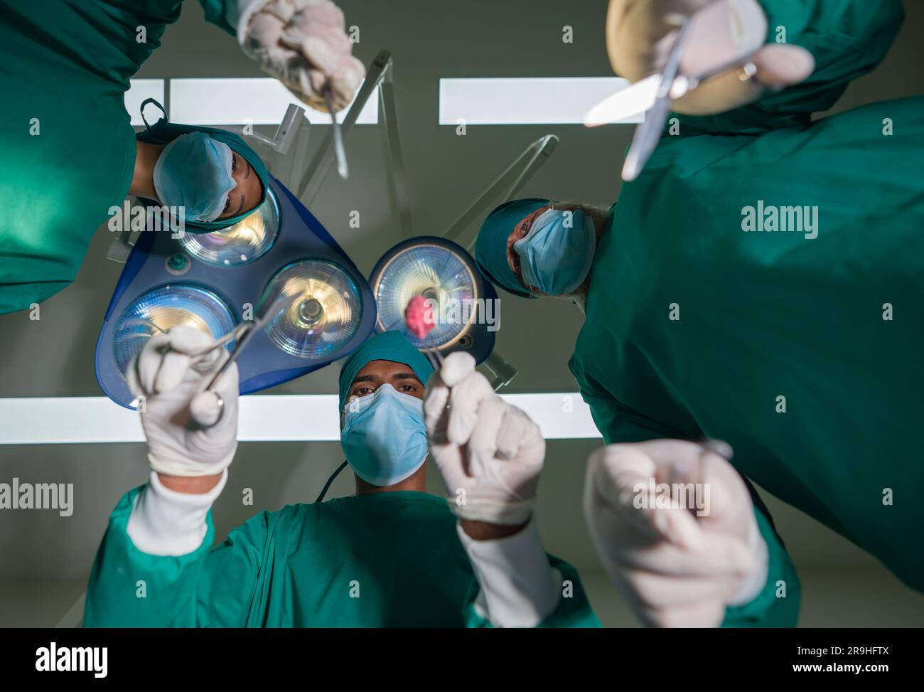 Concetto di assistenza chirurgica di emergenza. Gruppo di chirurghi e infermieri in uniforme da camice verde chirurgica che esegue operazioni chirurgiche in sala operatoria. vi inferiore Foto Stock