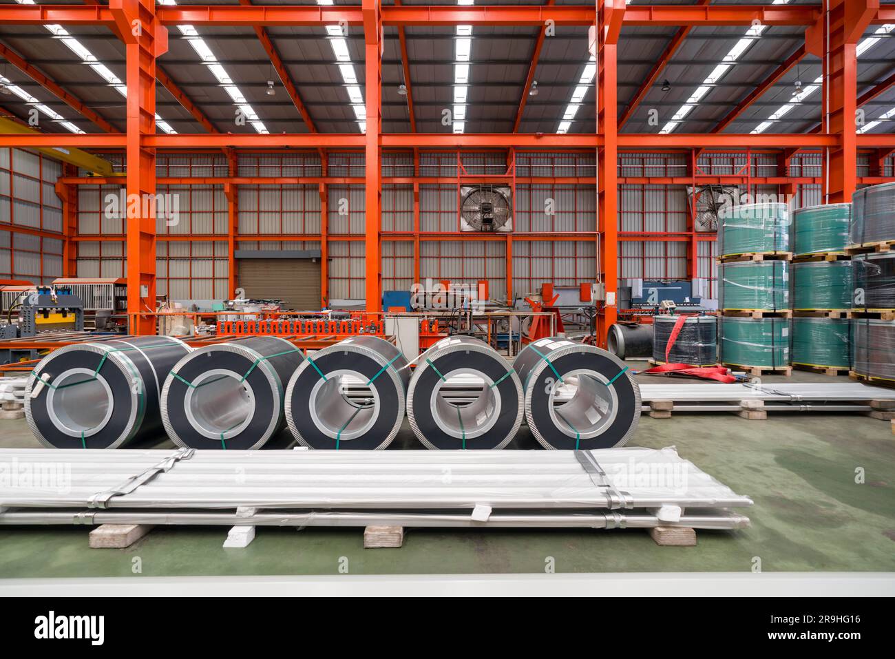 Il rotolo di lamiera di acciaio e le lamiere di metallo sono posizionati sul pavimento nella fabbrica di lamiere. Foto Stock