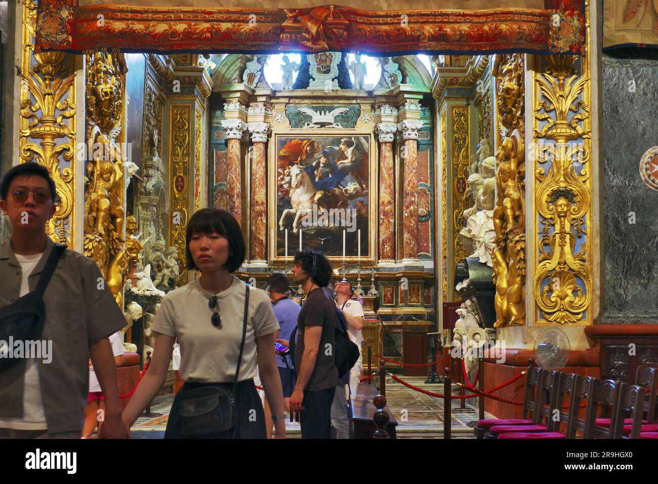 Una coppia sfocata di turisti asiatici esce dalla Cappella della Langue di Aragona all'interno di St Co-cattedrale di Giovanni a la Valletta, Malta Foto Stock