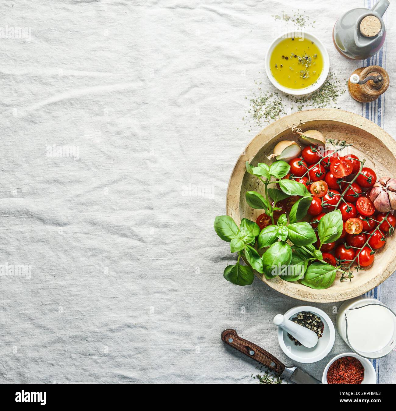 Pomodori e basilico in legno sul tavolo da cucina con ingredienti per cucinare in modo sano la crema di pomodoro, vista dall'alto. Confine Foto Stock