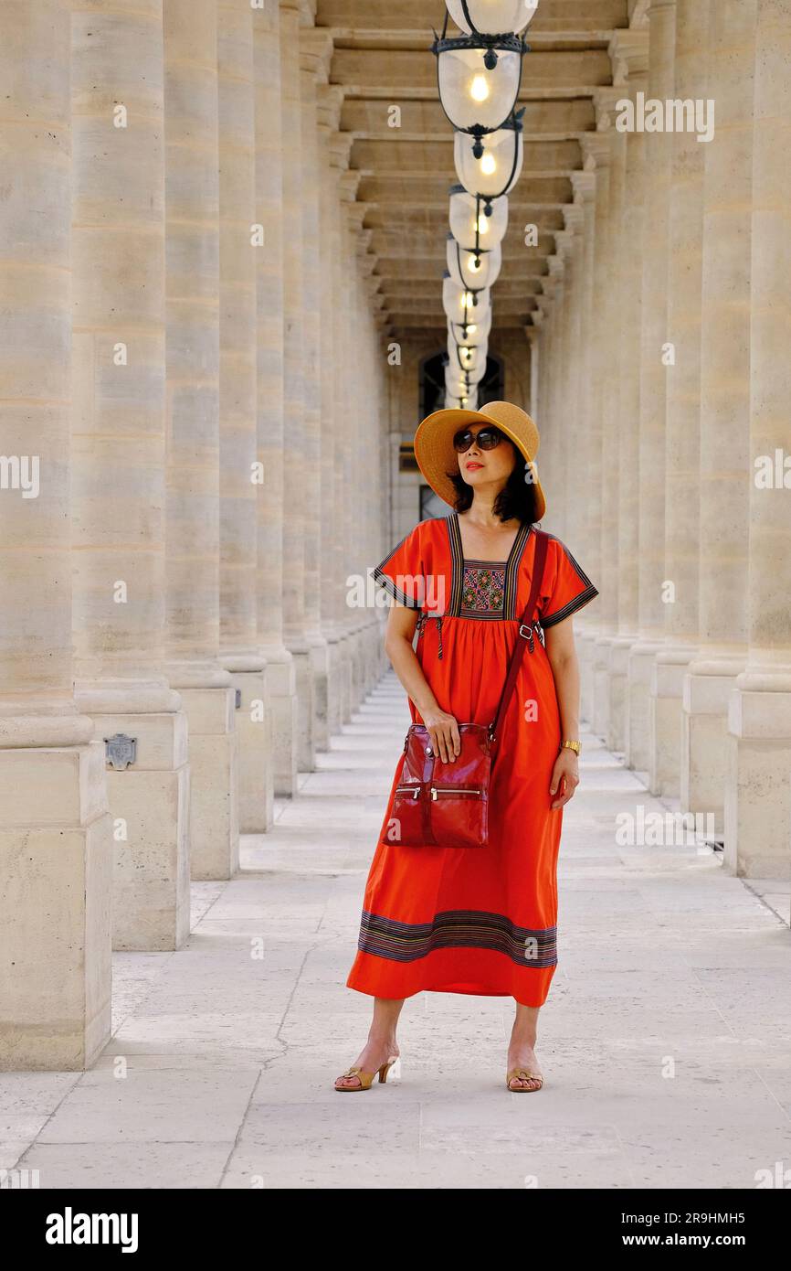 Tra le colonne del Palais Royal che indossa un abito contadino russo, una donna asiatica matura e glamour a Parigi Foto Stock