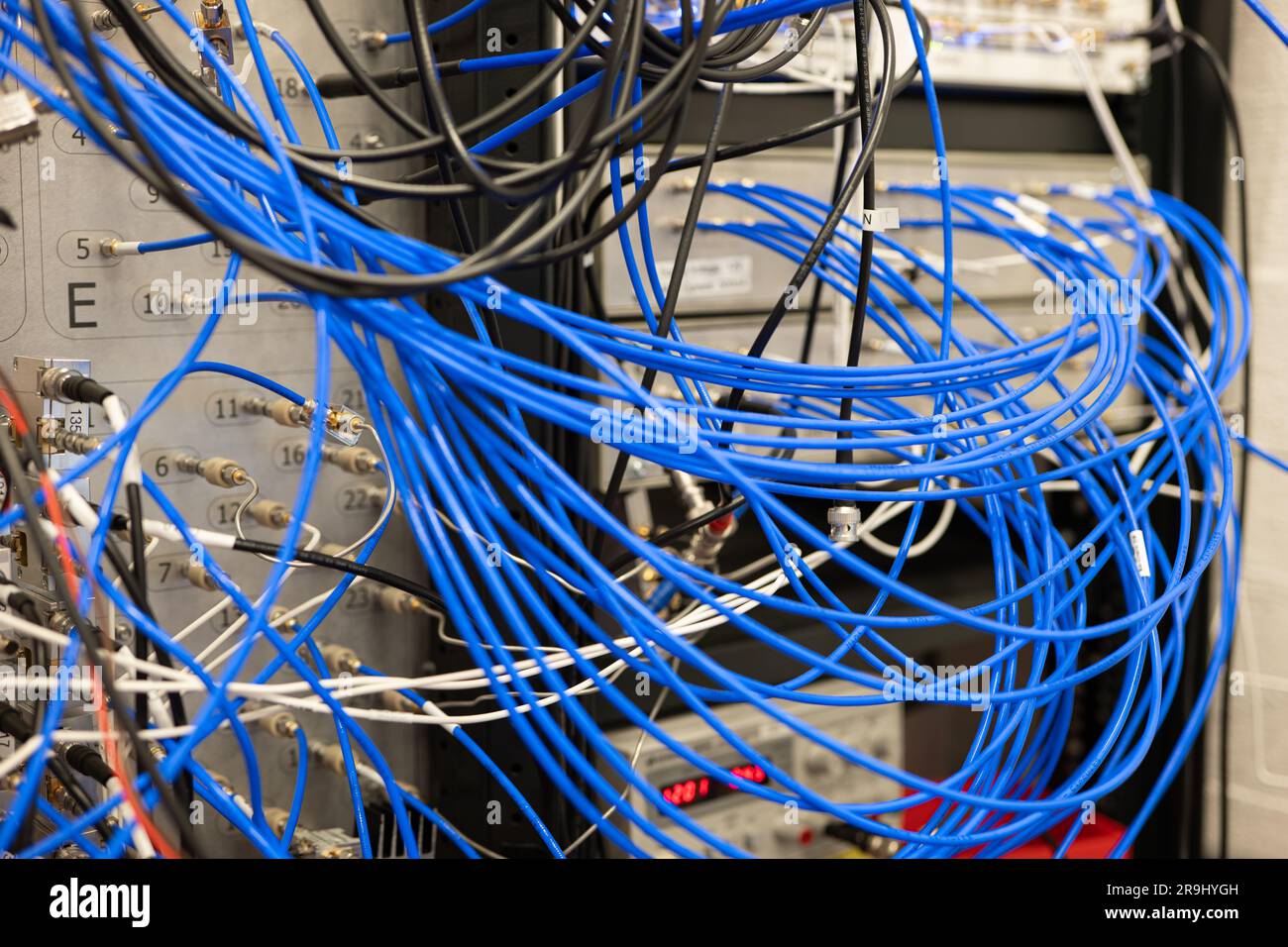 Cavi elettrici blu disordinati che si collegano ai dispositivi di laboratorio industriali, senza persone. Foto Stock