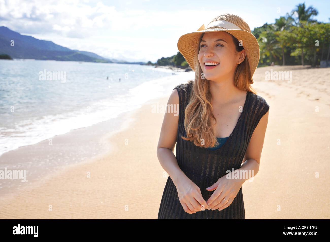 Ritratto di una bella ragazza che indossa abiti estivi e cappello di paglia sulla spiaggia tropicale Foto Stock
