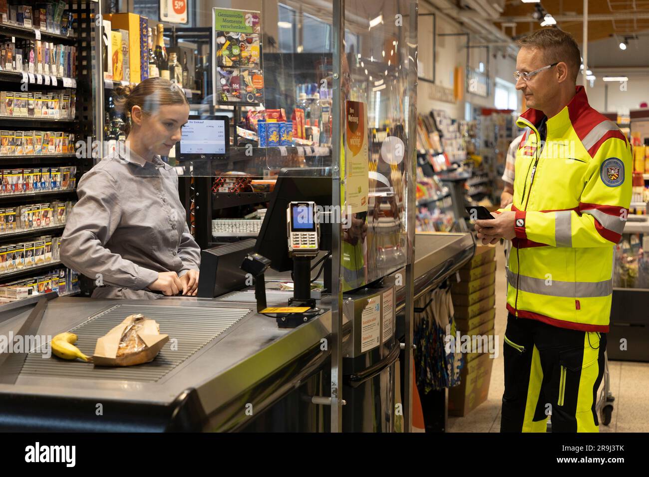 27 giugno 2023, Assia, Brachttal: Un medico di emergenza si trova in un negozio di supermercato (scena posta). La campagna "corsia di emergenza al checkout" nel distretto di Mainz-Kinzig ha lo scopo di accelerare l'elaborazione dei servizi di emergenza al checkout in futuro. Foto: Tim Würz/dpa Foto Stock