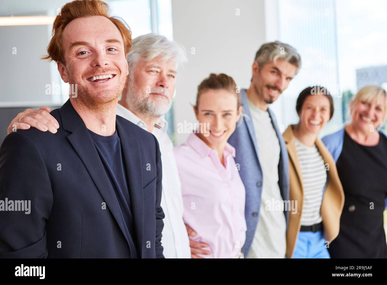 Colleghi d'affari sorridenti, uomini e donne, che si trovano fianco a fianco Foto Stock