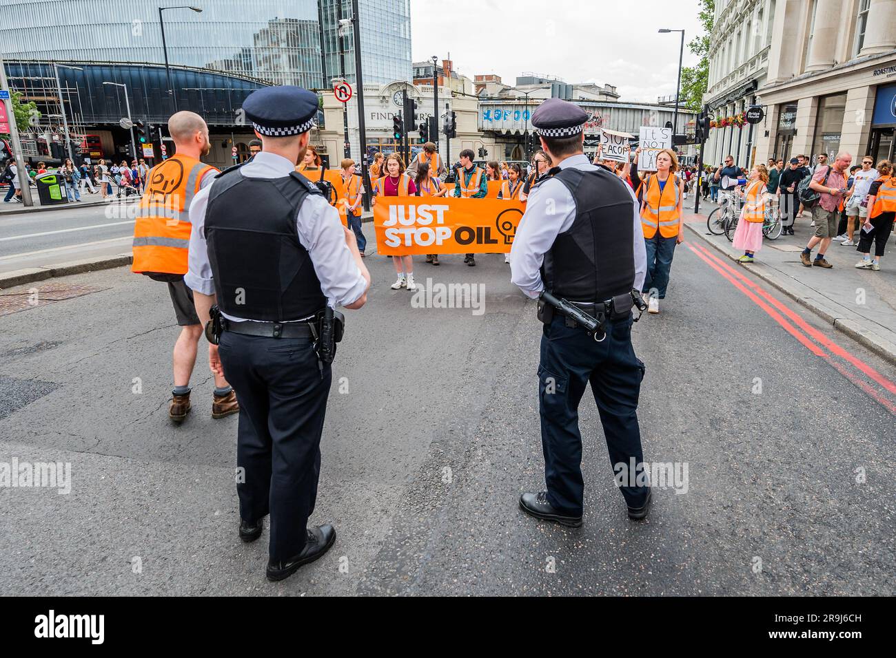 Londra, Regno Unito. 27 giugno 2023. La polizia inizia immediatamente ad avvertire la protesta che stanno bloccando la strada e causando e offendere ai sensi della sezione 12 del Public Order Act - basta fermare la protesta petrolifera al London Bridge. L'obiettivo generale del gruppo è quello di convincere il governo a fermare tutti i nuovi giacimenti petroliferi nell'ambito degli sforzi volti ad evitare la crisi climatica. Crediti: Guy Bell/Alamy Live News Foto Stock