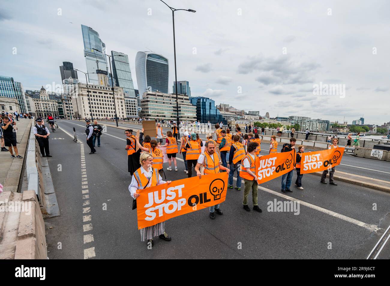 Londra, Regno Unito. 27 giugno 2023. La polizia inizia immediatamente ad avvertire la protesta che stanno bloccando la strada e causando e offendere ai sensi della sezione 12 del Public Order Act - basta fermare la protesta petrolifera al London Bridge. L'obiettivo generale del gruppo è quello di convincere il governo a fermare tutti i nuovi giacimenti petroliferi nell'ambito degli sforzi volti ad evitare la crisi climatica. Crediti: Guy Bell/Alamy Live News Foto Stock