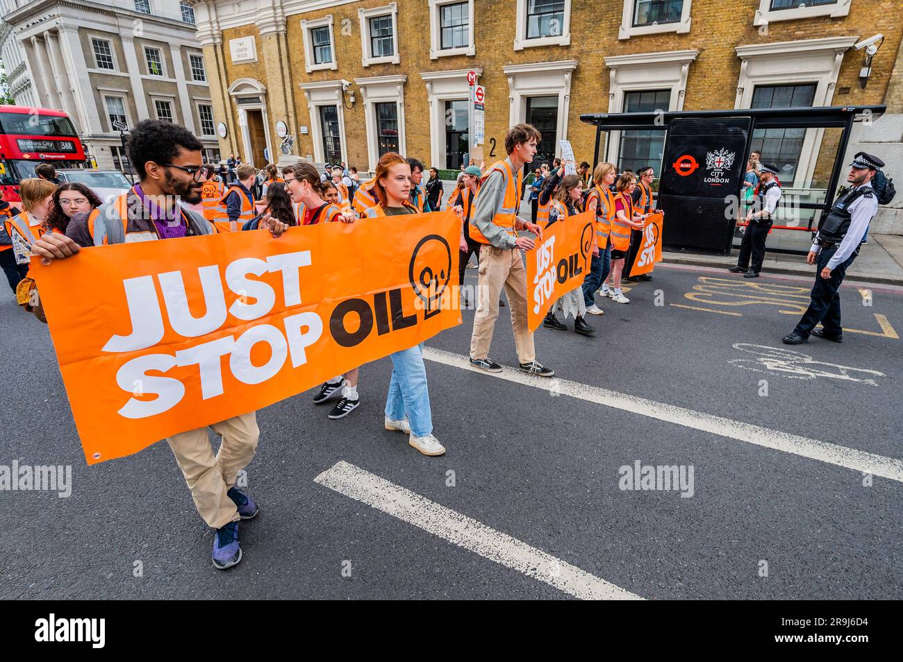 Londra, Regno Unito. 27 giugno 2023. La polizia inizia immediatamente ad avvertire la protesta che stanno bloccando la strada e causando e offendere ai sensi della sezione 12 del Public Order Act - basta fermare la protesta petrolifera al London Bridge. L'obiettivo generale del gruppo è quello di convincere il governo a fermare tutti i nuovi giacimenti petroliferi nell'ambito degli sforzi volti ad evitare la crisi climatica. Crediti: Guy Bell/Alamy Live News Foto Stock