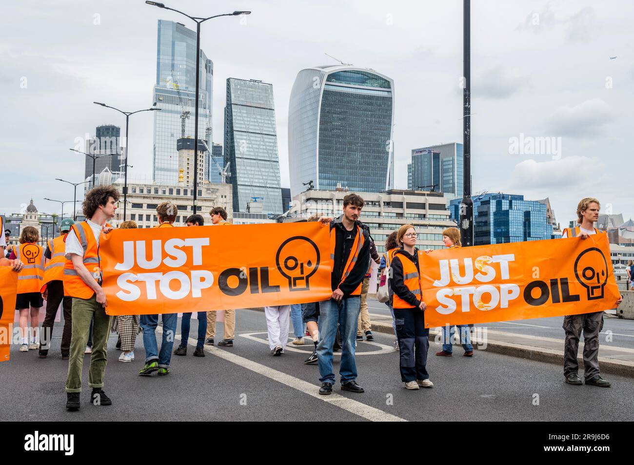 Londra, Regno Unito. 27 giugno 2023. La polizia inizia immediatamente ad avvertire la protesta che stanno bloccando la strada e causando e offendere ai sensi della sezione 12 del Public Order Act - basta fermare la protesta petrolifera al London Bridge. L'obiettivo generale del gruppo è quello di convincere il governo a fermare tutti i nuovi giacimenti petroliferi nell'ambito degli sforzi volti ad evitare la crisi climatica. Crediti: Guy Bell/Alamy Live News Foto Stock