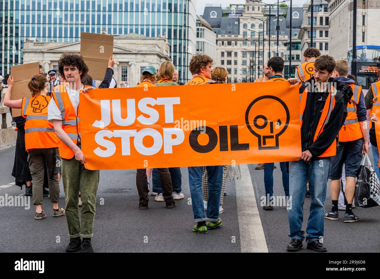 Londra, Regno Unito. 27 giugno 2023. La polizia inizia immediatamente ad avvertire la protesta che stanno bloccando la strada e causando e offendere ai sensi della sezione 12 del Public Order Act - basta fermare la protesta petrolifera al London Bridge. L'obiettivo generale del gruppo è quello di convincere il governo a fermare tutti i nuovi giacimenti petroliferi nell'ambito degli sforzi volti ad evitare la crisi climatica. Crediti: Guy Bell/Alamy Live News Foto Stock