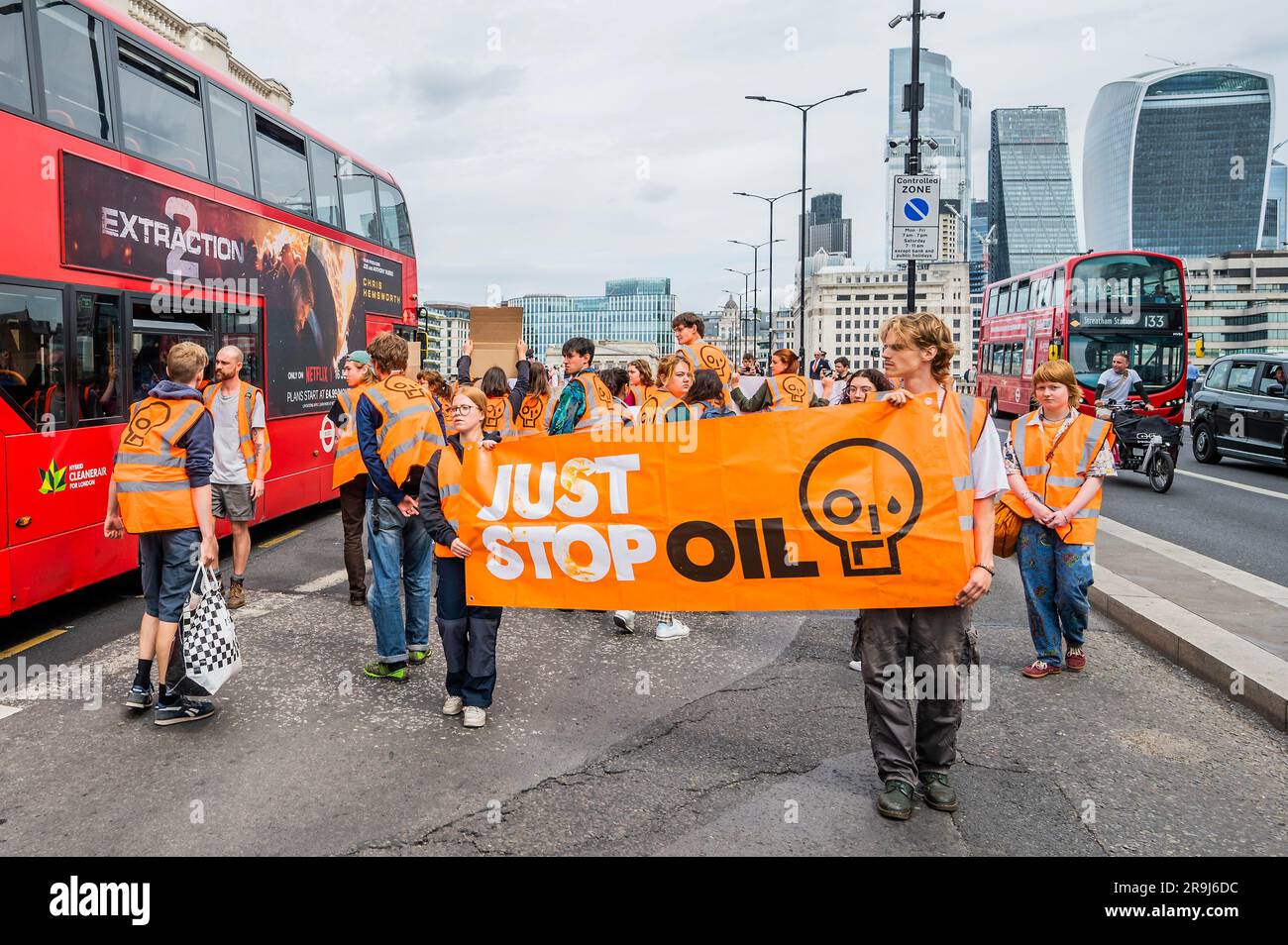 Londra, Regno Unito. 27 giugno 2023. La polizia inizia immediatamente ad avvertire la protesta che stanno bloccando la strada e causando e offendere ai sensi della sezione 12 del Public Order Act, ma lasciano passare autobus e biciclette - basta fermare la protesta petrolifera al London Bridge. L'obiettivo generale del gruppo è quello di convincere il governo a fermare tutti i nuovi giacimenti petroliferi nell'ambito degli sforzi volti ad evitare la crisi climatica. Crediti: Guy Bell/Alamy Live News Foto Stock