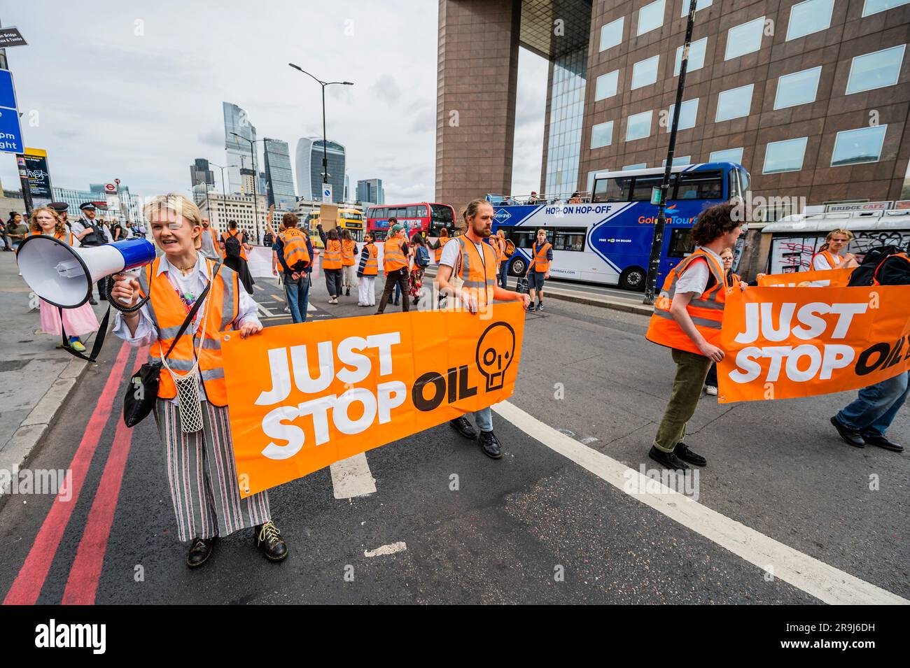 Londra, Regno Unito. 27 giugno 2023. La polizia inizia immediatamente ad avvertire la protesta che stanno bloccando la strada e causando e offendere ai sensi della sezione 12 del Public Order Act, ma lasciano passare autobus e biciclette - basta fermare la protesta petrolifera al London Bridge. L'obiettivo generale del gruppo è quello di convincere il governo a fermare tutti i nuovi giacimenti petroliferi nell'ambito degli sforzi volti ad evitare la crisi climatica. Crediti: Guy Bell/Alamy Live News Foto Stock