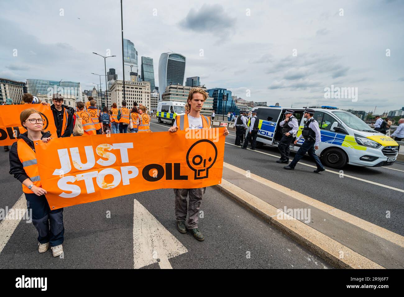 Londra, Regno Unito. 27 giugno 2023. La polizia inizia immediatamente ad avvertire la protesta che stanno bloccando la strada e causando e offendere ai sensi della sezione 12 del Public Order Act - basta fermare la protesta petrolifera al London Bridge. L'obiettivo generale del gruppo è quello di convincere il governo a fermare tutti i nuovi giacimenti petroliferi nell'ambito degli sforzi volti ad evitare la crisi climatica. Crediti: Guy Bell/Alamy Live News Foto Stock