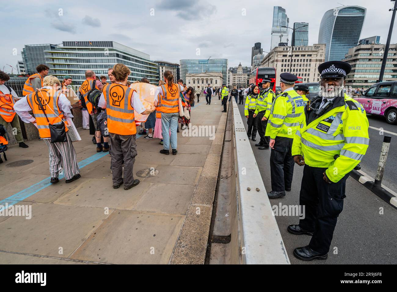 Londra, Regno Unito. 27 giugno 2023. L'ufficiale anziano presente dà un ultimo avvertimento e i manifestanti lasciano la strada dopo averla ammassata a metà del ponte - la polizia aveva già avvertito che stavano causando e offendere ai sensi della sezione 12 del Public Order Act - basta fermare la protesta petrolifera al London Bridge. L'obiettivo generale del gruppo è quello di convincere il governo a fermare tutti i nuovi giacimenti petroliferi nell'ambito degli sforzi volti ad evitare la crisi climatica. Crediti: Guy Bell/Alamy Live News Foto Stock