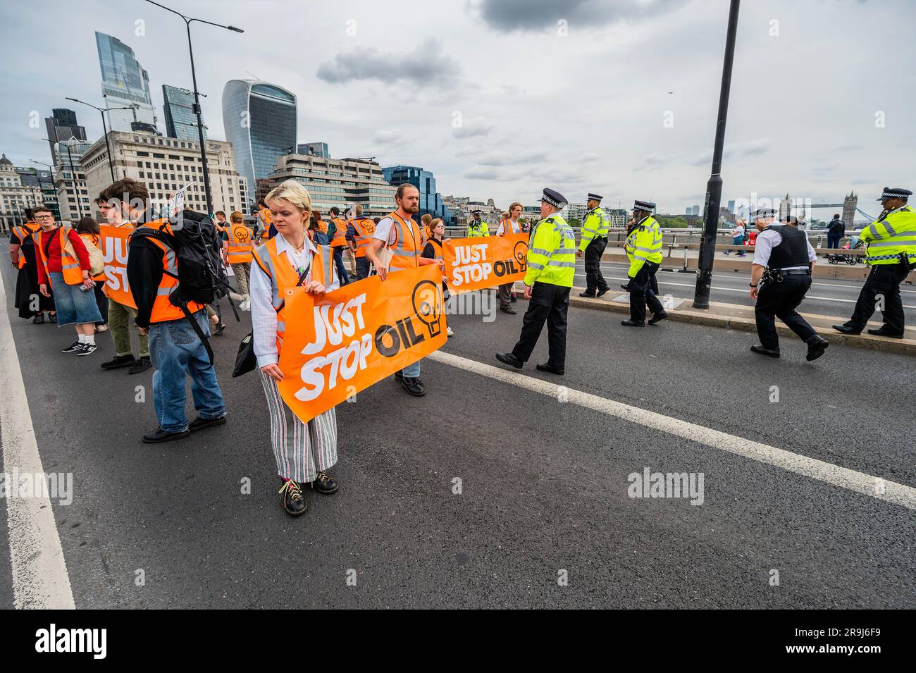 Londra, Regno Unito. 27 giugno 2023. La polizia inizia immediatamente ad avvertire la protesta che stanno bloccando la strada e causando e offendere ai sensi della sezione 12 del Public Order Act - basta fermare la protesta petrolifera al London Bridge. L'obiettivo generale del gruppo è quello di convincere il governo a fermare tutti i nuovi giacimenti petroliferi nell'ambito degli sforzi volti ad evitare la crisi climatica. Crediti: Guy Bell/Alamy Live News Foto Stock