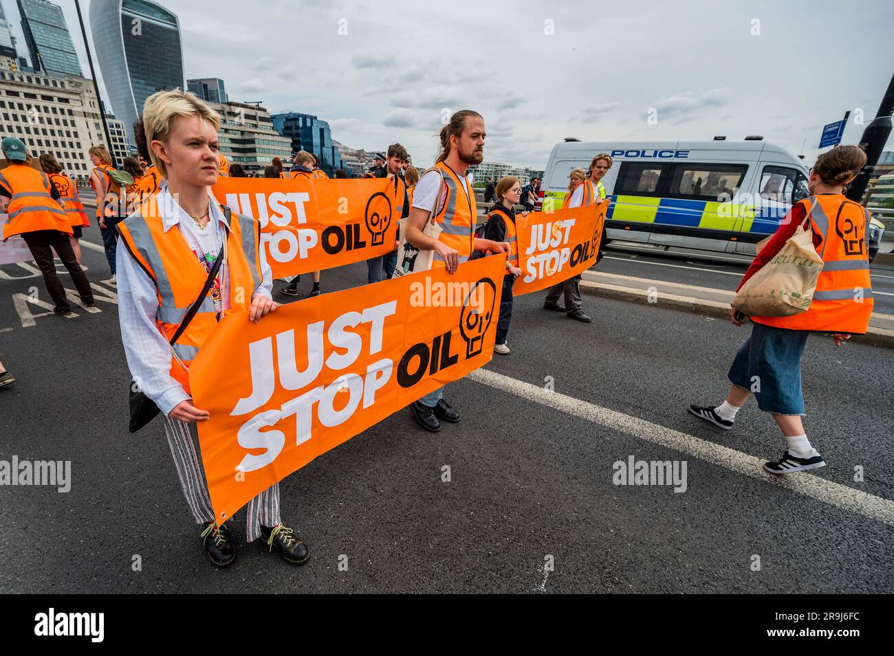 Londra, Regno Unito. 27 giugno 2023. La polizia inizia immediatamente ad avvertire la protesta che stanno bloccando la strada e causando e offendere ai sensi della sezione 12 del Public Order Act - basta fermare la protesta petrolifera al London Bridge. L'obiettivo generale del gruppo è quello di convincere il governo a fermare tutti i nuovi giacimenti petroliferi nell'ambito degli sforzi volti ad evitare la crisi climatica. Crediti: Guy Bell/Alamy Live News Foto Stock