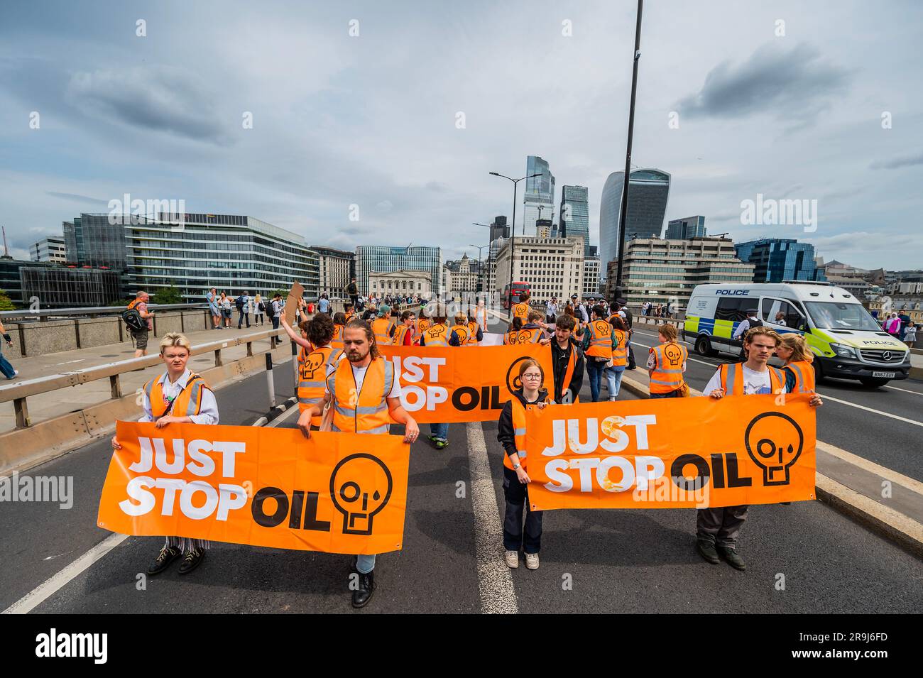 Londra, Regno Unito. 27 giugno 2023. La polizia inizia immediatamente ad avvertire la protesta che stanno bloccando la strada e causando e offendere ai sensi della sezione 12 del Public Order Act - basta fermare la protesta petrolifera al London Bridge. L'obiettivo generale del gruppo è quello di convincere il governo a fermare tutti i nuovi giacimenti petroliferi nell'ambito degli sforzi volti ad evitare la crisi climatica. Crediti: Guy Bell/Alamy Live News Foto Stock