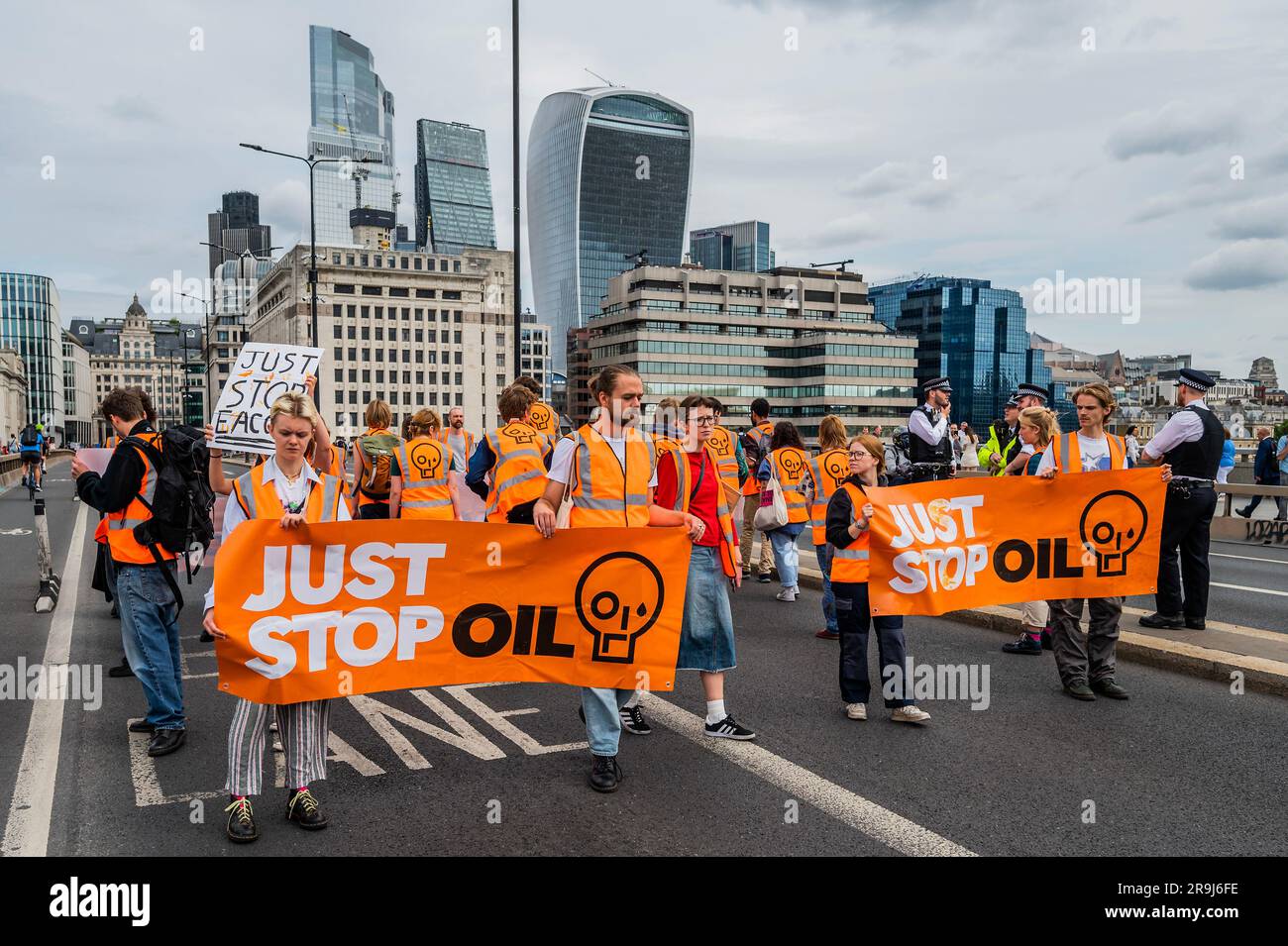 Londra, Regno Unito. 27 giugno 2023. La polizia inizia immediatamente ad avvertire la protesta che stanno bloccando la strada e causando e offendere ai sensi della sezione 12 del Public Order Act - basta fermare la protesta petrolifera al London Bridge. L'obiettivo generale del gruppo è quello di convincere il governo a fermare tutti i nuovi giacimenti petroliferi nell'ambito degli sforzi volti ad evitare la crisi climatica. Crediti: Guy Bell/Alamy Live News Foto Stock