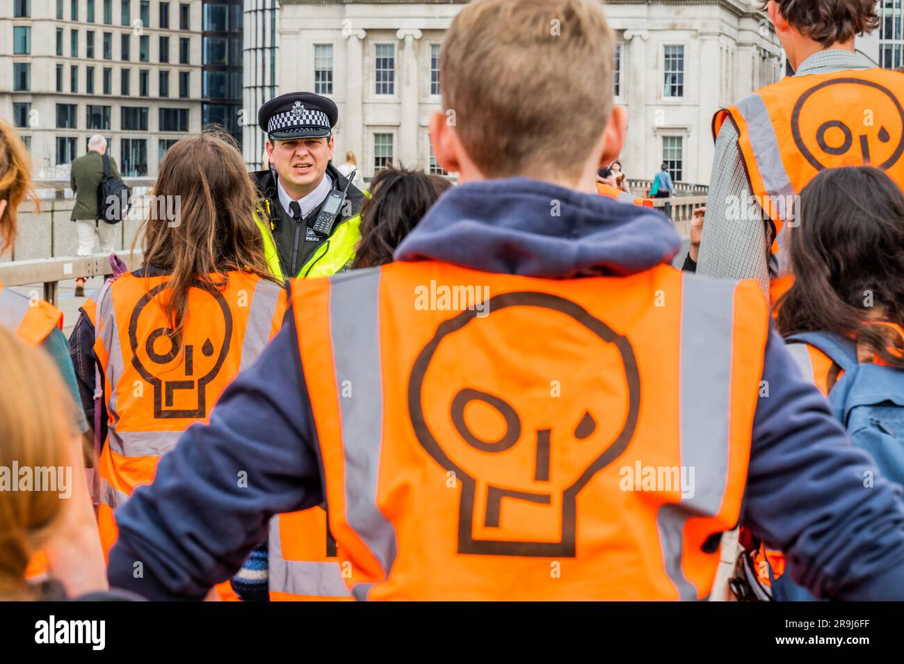 Londra, Regno Unito. 27 giugno 2023. L'ufficiale anziano presente dà un ultimo avvertimento e i manifestanti lasciano la strada dopo averla ammassata a metà del ponte - la polizia aveva già avvertito che stavano causando e offendere ai sensi della sezione 12 del Public Order Act - basta fermare la protesta petrolifera al London Bridge. L'obiettivo generale del gruppo è quello di convincere il governo a fermare tutti i nuovi giacimenti petroliferi nell'ambito degli sforzi volti ad evitare la crisi climatica. Crediti: Guy Bell/Alamy Live News Foto Stock